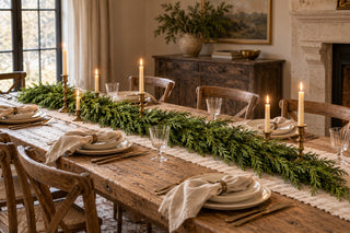 72-inch Real Touch cedar garland styled along an aged wood Christmas dining table with cream place settings, linen napkins, and brass candlesticks.
