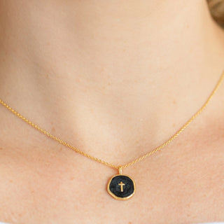 Gold necklace with a black pendant on a person's neck