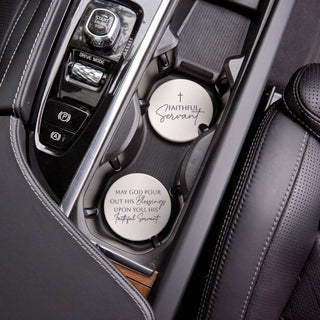 Cream and navy Faithful Servant Christian ceramic coasters displayed in a vehicle’s front cup holders.