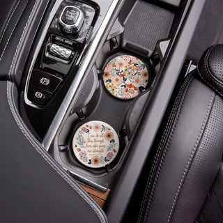 Garden floral and Philippians 4:13 ceramic coasters displayed in a vehicle’s front cup holders.