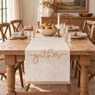 Beige Gather embroidered table runner styled on a warm wood dining table with neutral place settings, pears, and brass candlesticks.