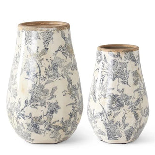 Two ceramic vases with a blue floral pattern on an off-white background, featuring a rustic brown rim, shown on a white studio background.