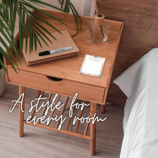 Small floral dry erase tile displayed on a wooden bedside table with a notebook, marker, and glass of water.